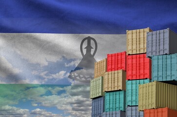 Lesotho flag and big stack of shipping cargo containers in docks with sky background close up