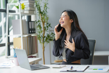 Young businesswoman in a modern office, happily laughing on a call, reflecting success and joy in her career as an entrepreneur