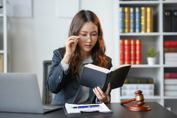 Focused asian lawyer reading law book at desk, showcasing expertise and dedication in legal field. Professional businesswoman providing legal advice with determination and intelligence