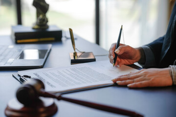 Legal professional is carefully reviewing and signing an important contract in their office, with a...