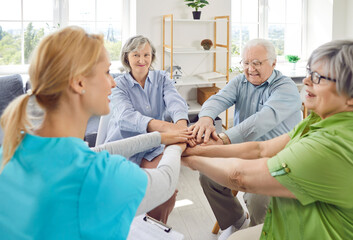 Senior people and care assistant team high five play in retirement home old age home nursing...