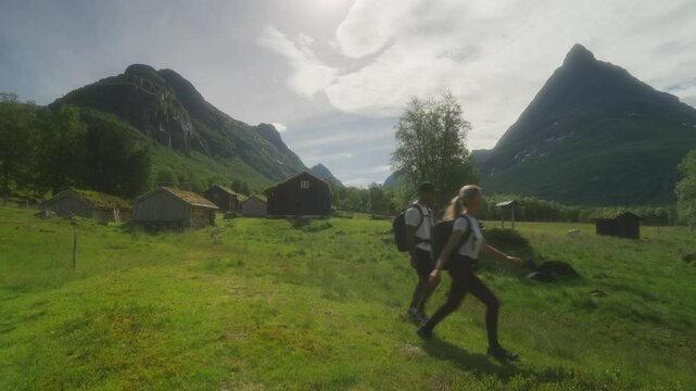 Hikers explore Innerdalen valley with Rennd&oslash;lsetra farm and Innerdalst&aring;rnet peak in the background