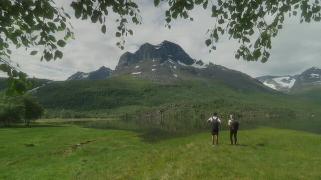 Young couple hiking in the lush green valley of Innerdalen, Norway with majestic mountains in the background