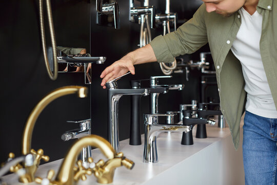 Young male customer looking at a wide range of modern good quality stainless steel faucets while choosing bathroom fittings at a hardware shop, shopping centre, or department store