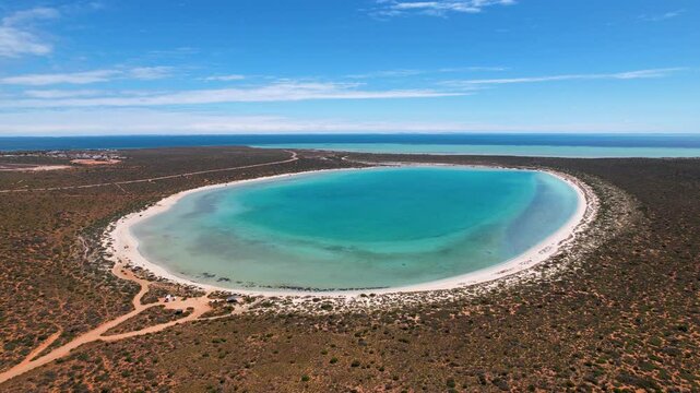4K drone video flying towards Little Lagoon in Monkey Mia, Western Australia. The beautiful lagoon sits just inland from the coast. It's a bright blue lagoon with white sand surrounding it.