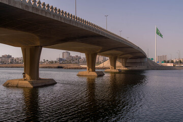 The large Saudi Arabia flag and the bridge across the Jeddah harbor in  Saudi Arabia, with the city...