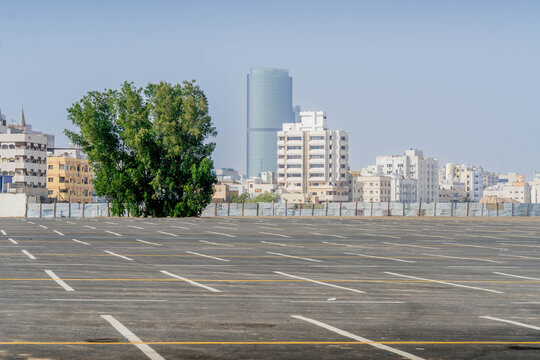 The empty parking lot and Jeddah panorama with the tall skyscrapers, business buildings, and modern architecture.
