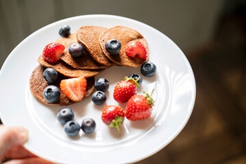 Sugar-free, gluten-free green buckwheat pancakes with strawberries and blueberries .
