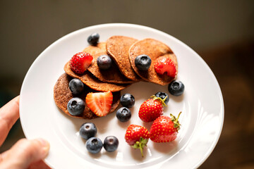 Sugar-free, gluten-free green buckwheat pancakes with strawberries and blueberries .