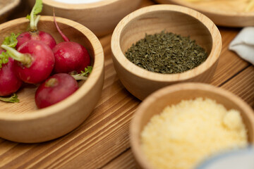 Close up in health food's Ingredients of special menu homemade cooking radish, garlic, salt, oregano, tomato and seasonings placing elements on preparing wooden table on blurred background. Postulate.