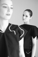 fashion black and white photo of two beautiful girls with dark hair and evening dress in white studio