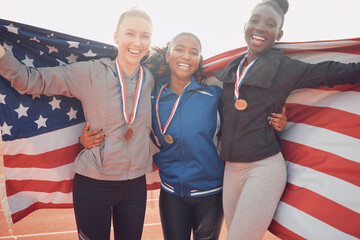 Success flag, athlete and portrait of woman team on race track for celebration, achievement and happy for medal. American group, people and smile for winning, event victory or relay champion on field