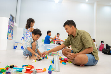 Dad play colorful toy block building with child boy and girl indoor playground