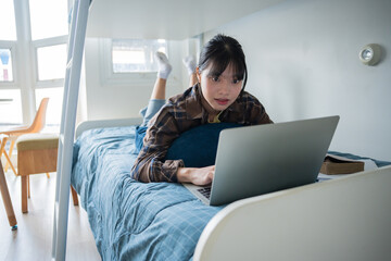 Naklejka premium asian girl lying use laptop on bed