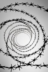 Black and white barbed wire in spiral on grey background
