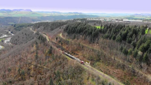 Aerial: train going uphill into the woods in the french Massif Central