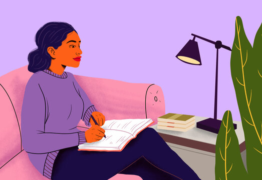 Woman writing in notebook sitting on couch