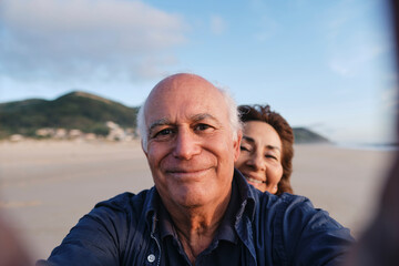 Smiling senior man taking selfie with woman at beach