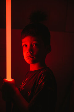 Boy holding lazer sword amidst red light