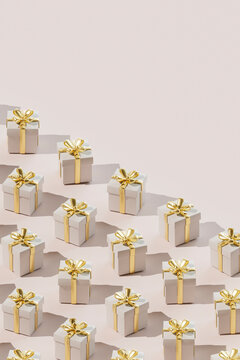 Repetition of gift boxes wrapped in golden ribbon over colored background