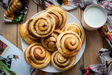 Vanilla buns with cinnamon. Sweet buns for breakfast on a wooden background. Homemade cinnamon rolls. View from above. Close-up