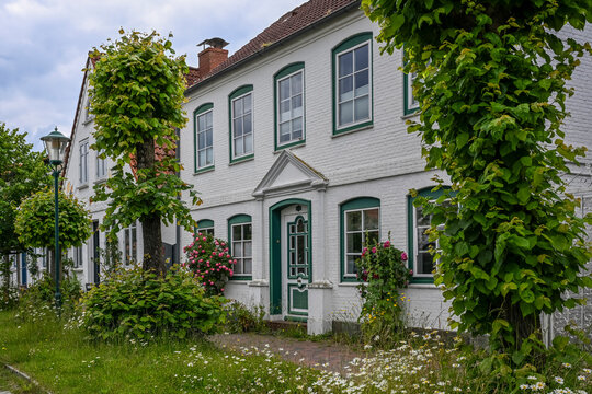 Germany, Schleswig-Holstein, Arnis, Trees and blooming flowers outside two storey building