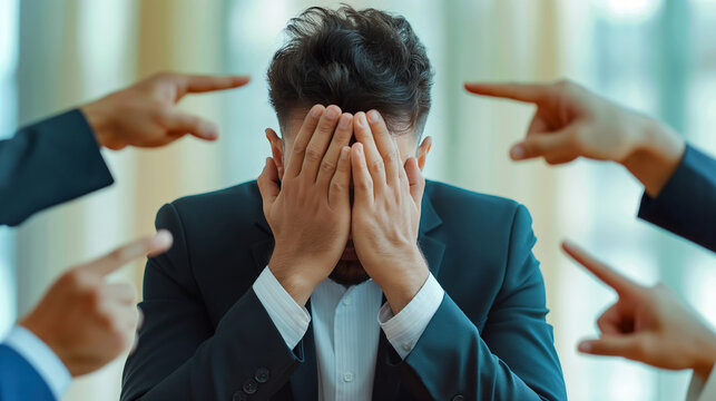 Stressed Man in Office Suit Overwhelmed by Pointing Fingers in Bright Room