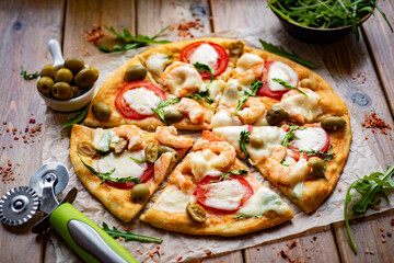 Italian pizza with tomatoes, shrimp, arugula and mozzarella. Homemade pizza for lunch. A slice of pizza for breakfast. Close-up