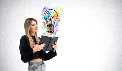 A woman is holding and reading a book, with a colorful lightbulb