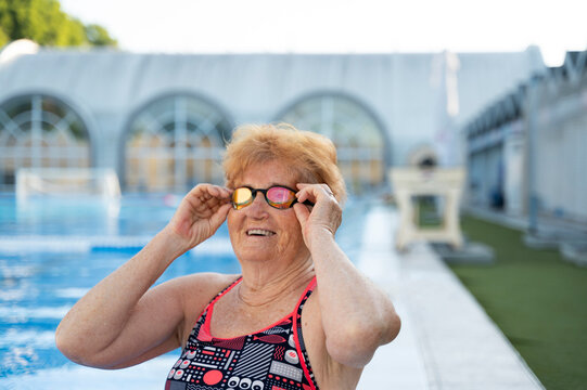 Happy senior woman wearing googles near swimming pool