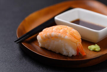 Nigiri sushi shrimp on wooden plate with wasabi and sauce, Japanese food