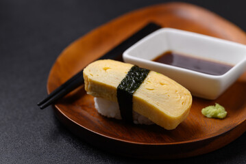 Nigiri sushi sweet egg (tamago) on wooden plate with wasabi and sauce, Japanese food