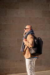 Mid aged man with mobile phone walking down the street