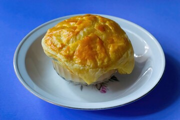 Homemade creamy soup dish with corn porridge and crispy cookies served on a white plate with a blue background seen from the front. Known as Zuppa Soup in Indonesia