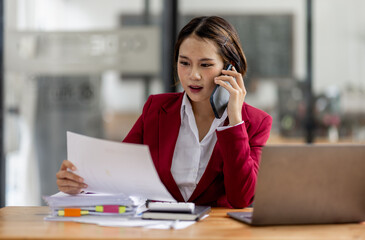 Cheerful business Asian woman accounting making telephone call share good news about project working in office workplace, business finance concept.	