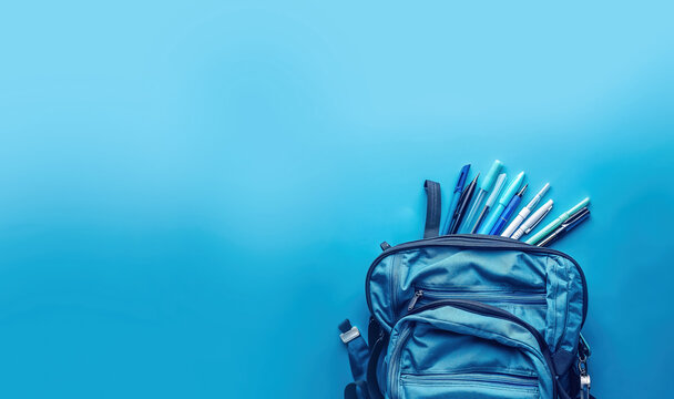 un sac &agrave; dos avec des fournitures scolaires (stylos) sur un fond bleu clair avec espace vide pour texte
