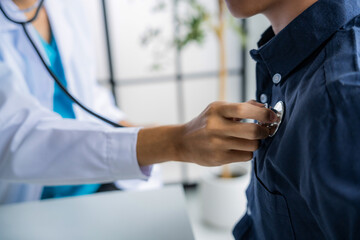 Doctor using stethoscope to check the heartbeat of the patient
