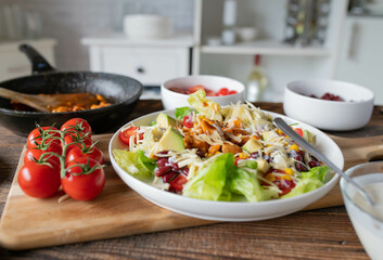 Tex mex barbecue chicken salad with kidney beans, avocado, cheese, lettuce, tomatoes, corn and ranch dressing on a plate