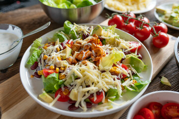 Tex mex barbecue chicken salad with kidney beans, avocado, cheese, lettuce, tomatoes, corn and...