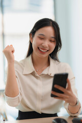 Happy Asian woman using smartphone and Excited