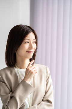 オフィスの窓際にいるスーツ姿の女性