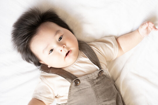 布団の上で仰向けでこちらを見ている赤ちゃん