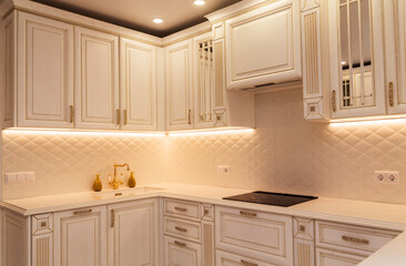 Elegant White Kitchen with Gold Accents and Lighting. Elegant white kitchen with gold-accented...