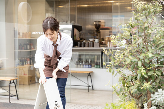 カフェの看板を出している女性