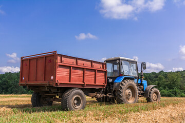 Tractor with a trailer is standing in the field waiting for the harvest