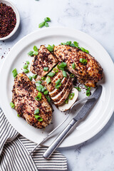 Fried sumak chicken with green onion on white plate.