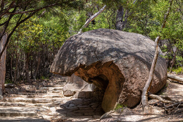 Overhanging boulder next to the stone step pathway of Freycinet National Park, Tasmania, Australia. The oldest of the Tasmanian National Parks and on the East Coast of the Island.