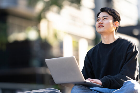 外で座ってノートパソコンで作業をしている男性