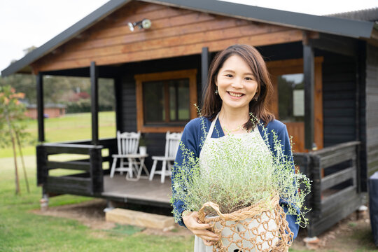 ハーブの鉢を持って笑っている女性