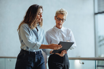 Woman and her administrative assistant use a digital tablet together in an office